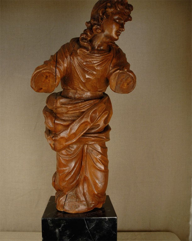 Large oak statue of a kneeling woman in flowing robes mounted on a later faux black marble painted wooden base.