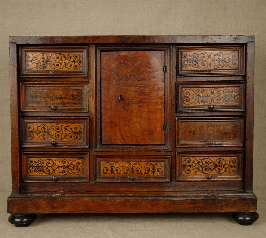 18th century, nine-drawer, single door cabinet with scrolling motifs.