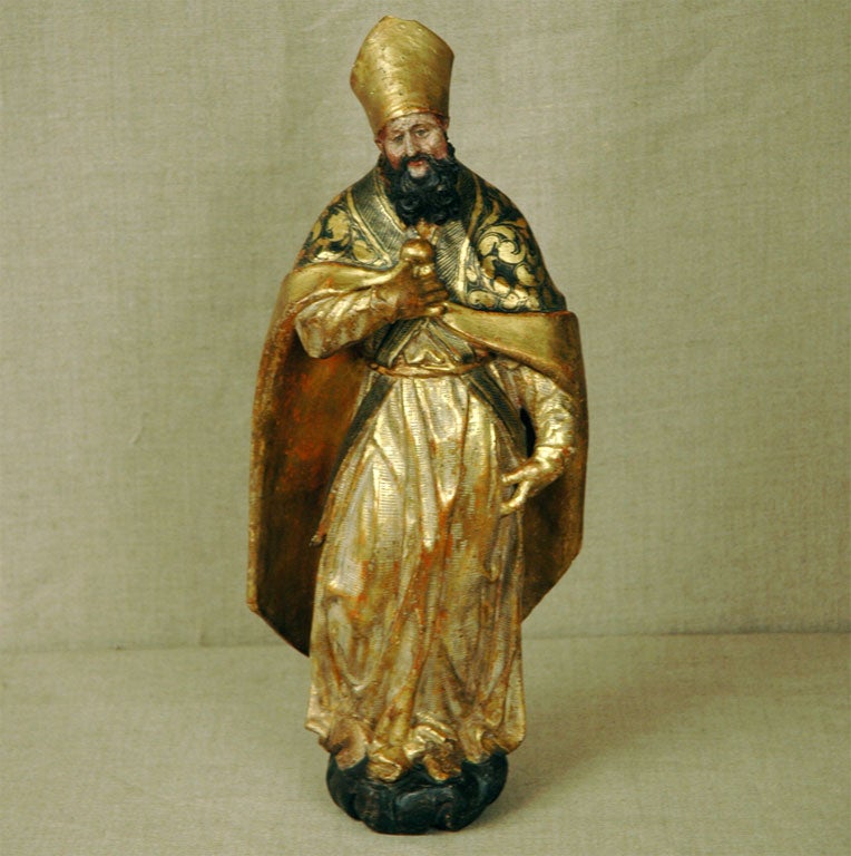 Vergoldete und bemalte Holzstatue eines Bischofs mit Hut in vollem Ornat.