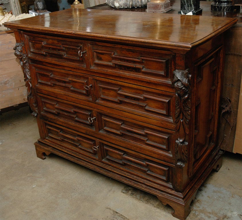 Tuscan chest with four, paneled drawers bordered by two caryatid reliefs, the whole atop bracket feet.  