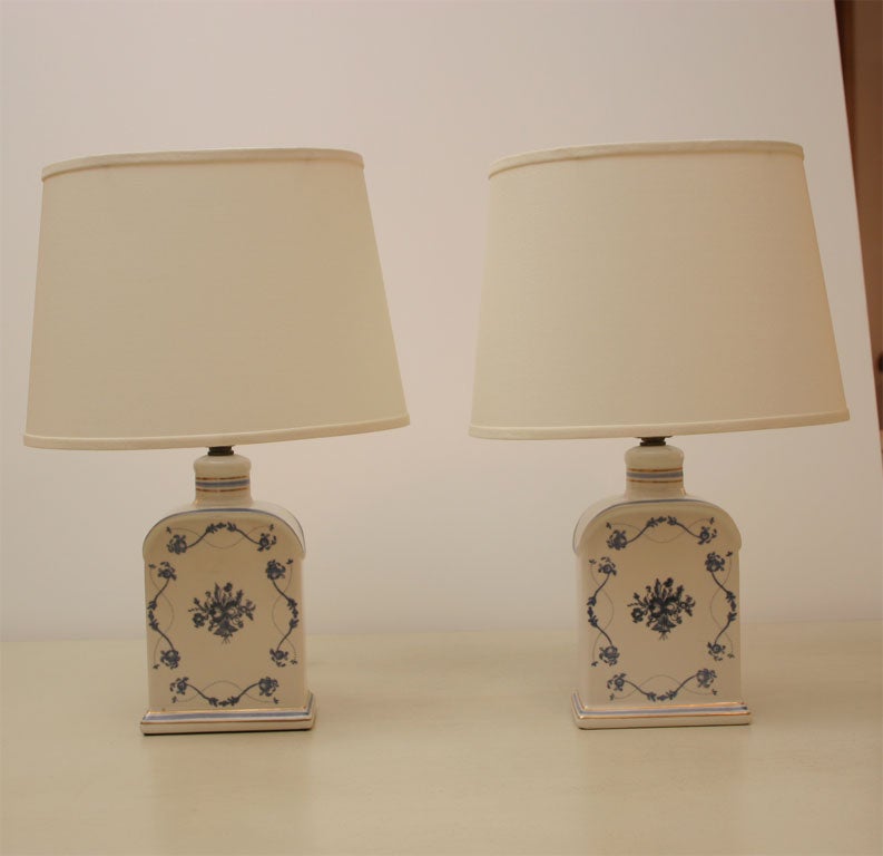 Blue floral decorative motif on body of lamp with gilt detailing on neck and base. White custom shades included.
