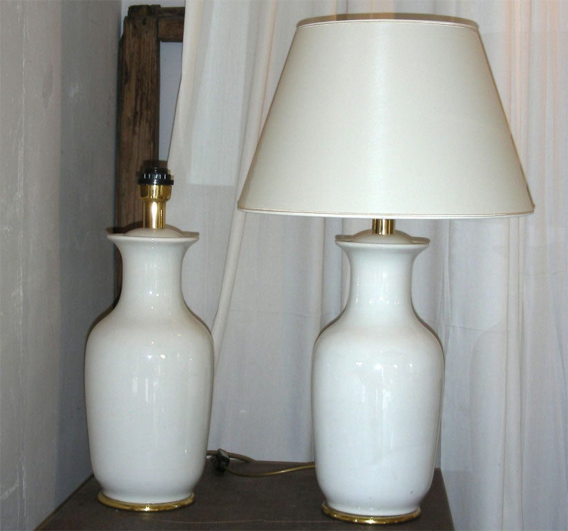 Two 1960s lamps in white porcelain with golden accents. Height with shade 74 cm., diameter of shade 44 cm.
