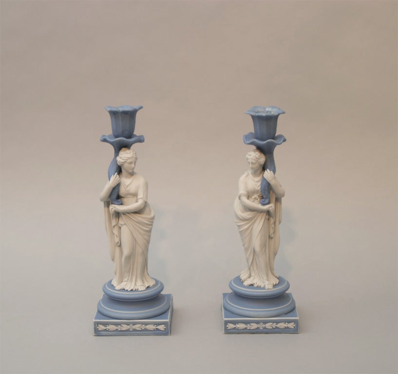 Rare pair of Wedgwood blue and white jasper figural candlesticks,. each with a classical woman holding a cornucopia, upper case mark