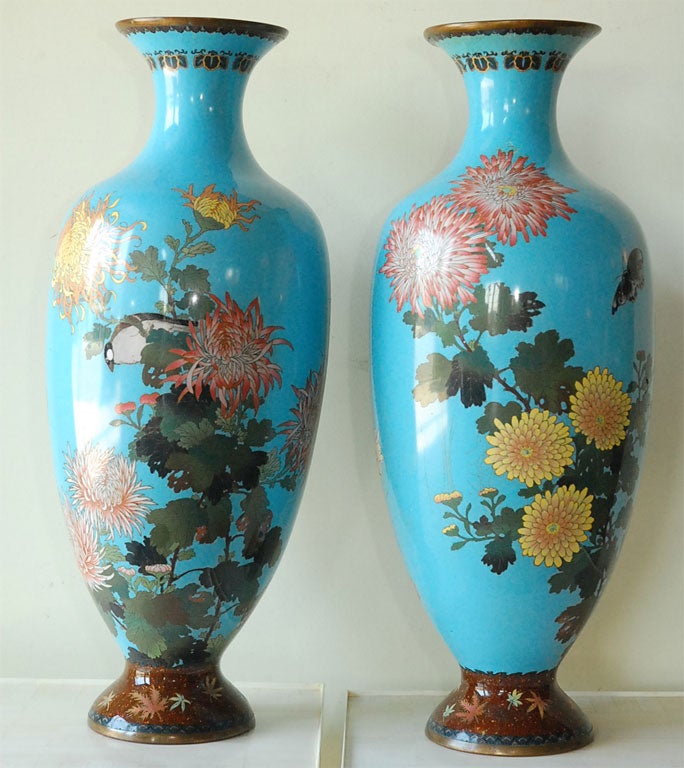 Striking pair of cloisonne vases depicting, birds, chrysanthemums and butterflies against a sky blue background.