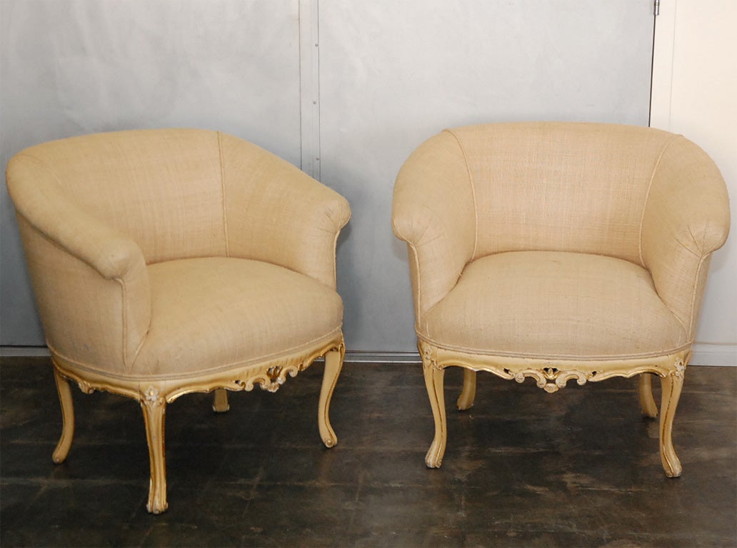 A pair of LXV style arm chairs standing on carved, painted and gilded out-turned legs. They have been upholstered in homespun linen.