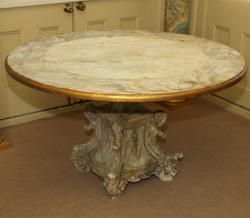 Surface of top is faux marbre bordered in a slight contrasting color and finished with a gilded edge. Mounted on a carved and painted boroque base. Good dining height.