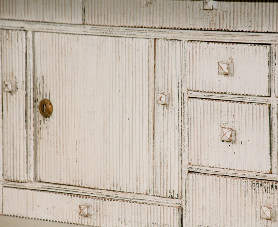 Gustavian style painted secretary with four large drawers below (one with carved relief detail) and thirteen compartments in the writing area. Features one lockable interior compartment. Rests on six scallop-edged fluted feet.