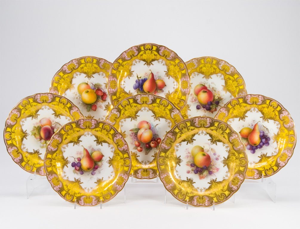 A rare set of 12 Royal Worcester hand painted dessert plates with saffron yellow borders, raised paste gold and applied enamel jewels. Each plate is uniquely decorated with different fruit motifs surrounded by a star-shaped white ground and framed
