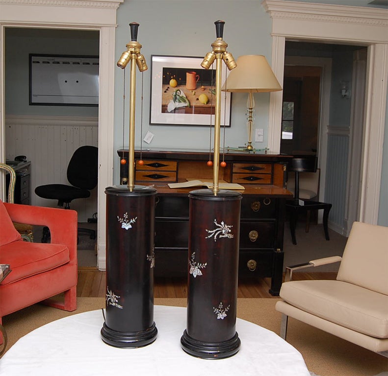 Tall cylindrical table lamps in black lacquer over wood, inlaid with mother-of-pearl flowers and peacocks; each with two lights on pullchains