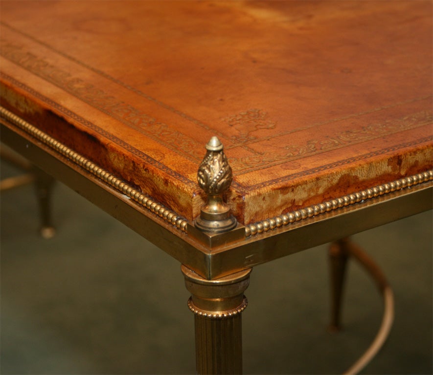 A pair of large square sofa end tables, raised on four round tapering legs joined by two curved stretchers with a round medallion in the center. The original leather tops are surrounded by a frame of beaded elements and finials on each corner,