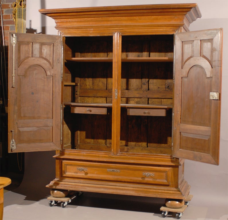 A large Dutch or German cabinet in walnut with bun feet, recessed paneled doors and moulded cornice, originating during the 19th century.