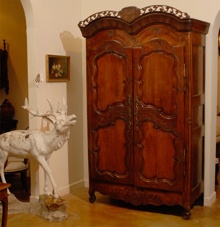 Armoire française de la fin du XVIIIe siècle en merisier de Rennes avec corniche percée, motifs floraux et coquillages. Née dans la capitale de la région orientale de la Bretagne, cette armoire en merisier français présente une étonnante corniche à