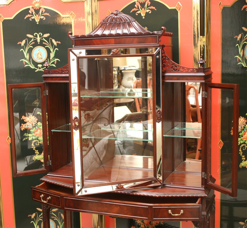 HAVING A CARVED AND MOLDED PAGODA CREST ABOVE A CENTRAL CABINET W/ MIRRORED INTERIOR & 2 GLASS SHELVES BEHIND A DOOR W/CENTRAL GLASS PANEL& MIRRORED SURROUNDS.SMALLER GLASS PANELLED CABINETS W/MIRRORED BACKS & OPEN FRETWORK GALLERIES FLANK THE MAIN