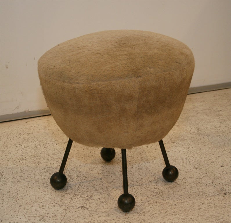 Rare French stool attributed Royere with four metal legs on hammered bronze ball feet. Upholstered in faux fur over wooden frame. 