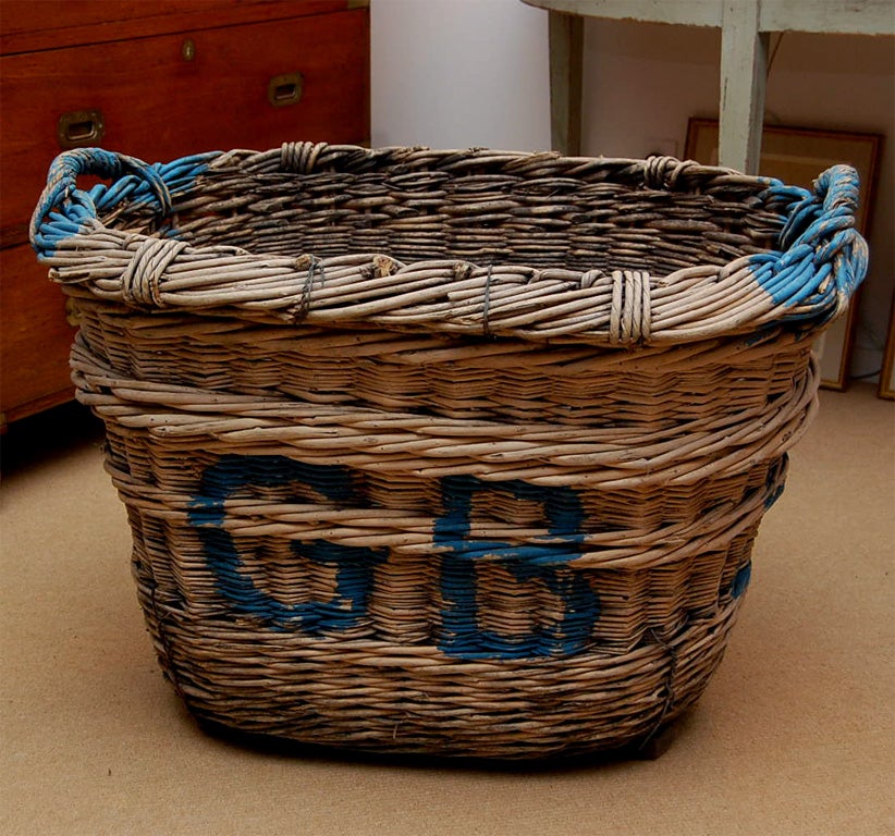 A large French turn-of-the-century Champagne Wicker Basket with original paint and original rope handles.  Wonderful for holding firewood.  Three available.