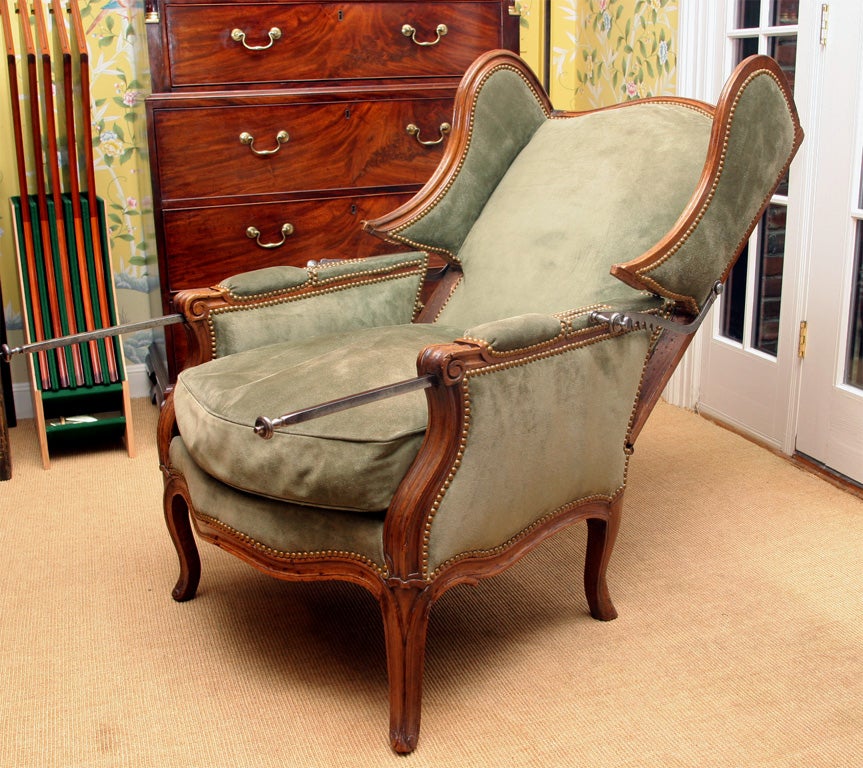 Rare provincial Louis XV carved walnut reclining wing chair with adjustable steel ratchet supports on cabriole legs.  One rear leg with a very old splice repair. French, c. 1750