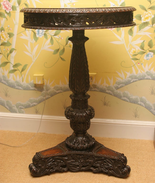 Beautifully carved Anglo-Indian circular tilt-top padouk wood table, having a moulded edge and intricately carved apron on a shaped stem with triangular pedestal base on scrolled feet, circa 1840.

Height: 30 1/2