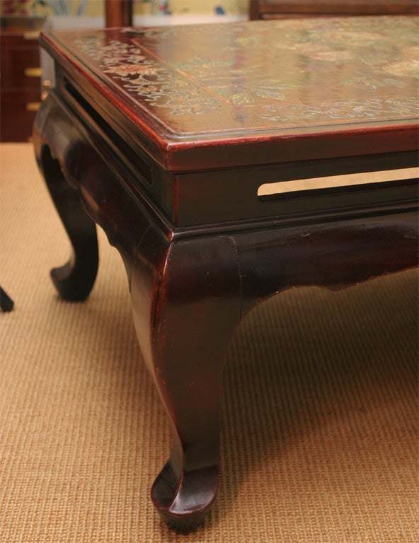 Antique coromandel wine colored polychrome lacquer low table, the carved top with birds and flowering branches above a recessed apron with horizontal cut-outs on cabriole legs, the carving colored in green, blue, orange and ivory, Chinese, 19th