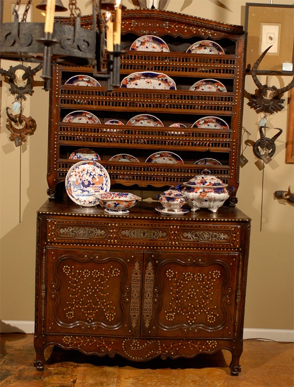 Chestnut deux corps vaisselier from Brittany; one drawer and two doors on the buffet base; 4 shelf plate rack on the top; decorated with an elaborate design of inlaid wood and brass tacks typical of the region; buffet side mounts are carved; the