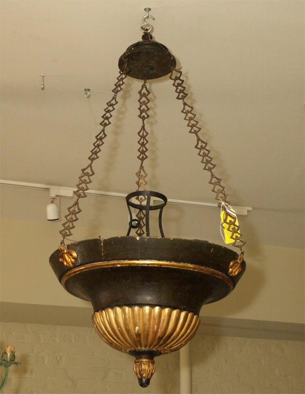 A WOODEN BOWL SHAPED LAMP WITH GILDED ACCENTS, THREE FORGED CHAINS IN BLACK IRON WITH GILT.