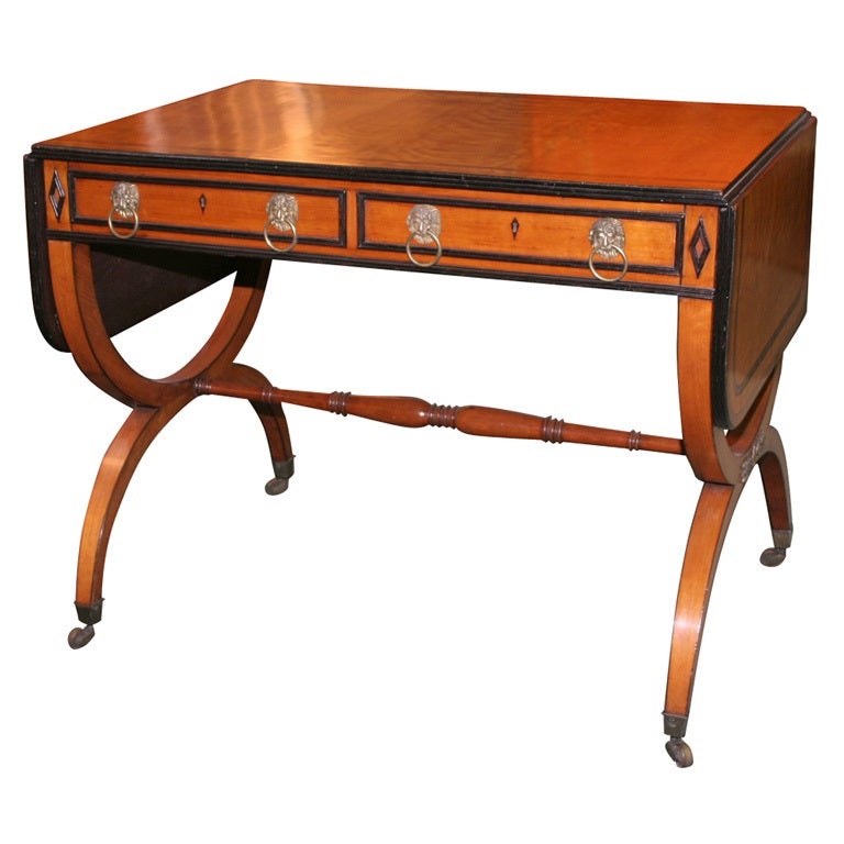 The top with rosewood and yew crossbanding over a reeded edge above simulated drawers with lion mask ring pulls; raised on Curule shaped legs joined by turned stretchers.