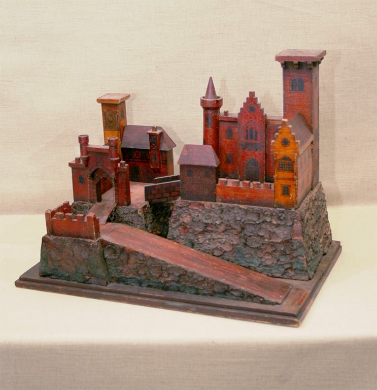 Painted Wooden Model of a Medieval Castle Compound with Gothic Windows, Battlements, Draw Bridge, and Parapets all Mounted on a Foundation Covered in Ruddy-Colored Painted Bark, 19th Century.<br />
<br />
22 inches wide x 13 inches deep x 16