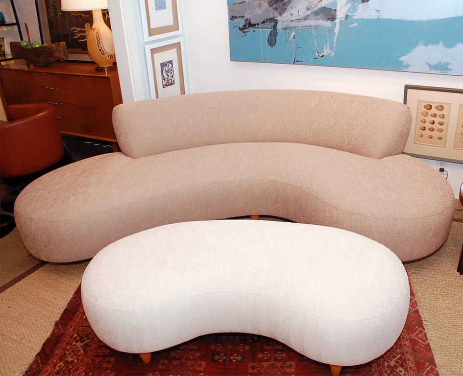 Our limited edition kidney shaped sofa and ottoman has a solid wood frame.  The sofa is upholstered in a taupe colored cotton blend and the ottoman is done in off white.