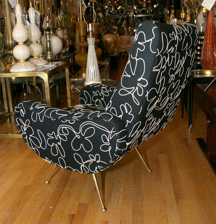 Pair of black upholstered arm chairs with splayed brass feet