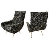 Pair of black upholstered arm chairs with splayed brass feet