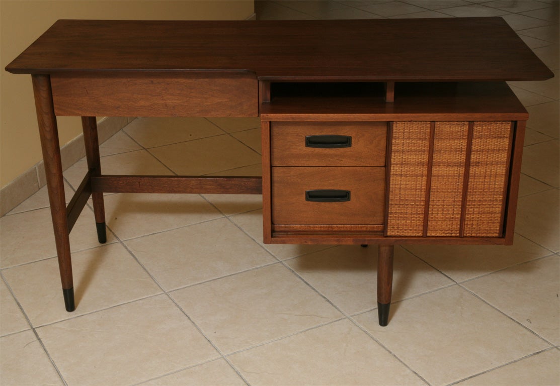 SOLD FEB 2009 Lovely floating top defines this handsome 50's walnut desk with five drawers and a sliding caned door that also flips to a walnut side.  Ebonized feet tips and metal drawer pulls.  Finished all around with an open book shelf on the