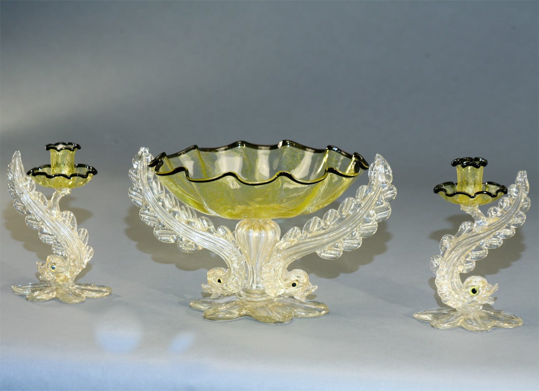 Fabulous Barovier three piece dramatic centerpiece set with hand blown double dolphin base supported lemon-yellow center bowl, with applied black trim and gold leaf inclusions. The bases are applied petal-shaped leaves supporting each piece. The