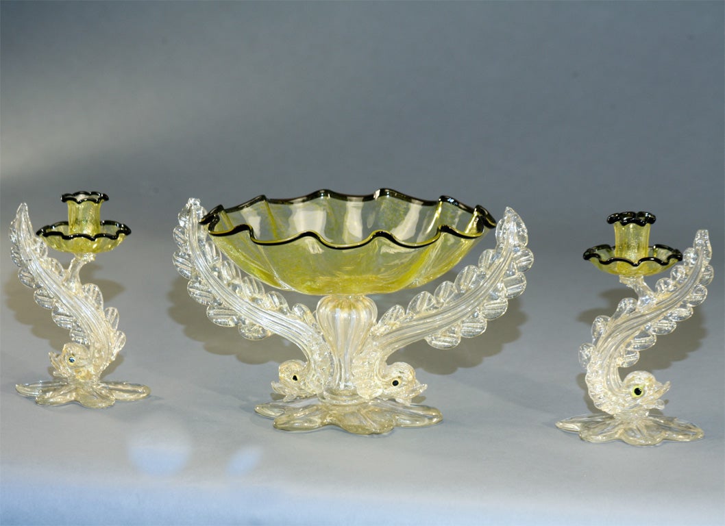Favoloso centrotavola Barovier in tre pezzi, con base a doppio delfino soffiato a mano e ciotola centrale giallo limone, con finiture nere applicate e inclusioni di foglia d'oro. Alle basi sono applicate foglie a forma di petalo che sostengono ogni