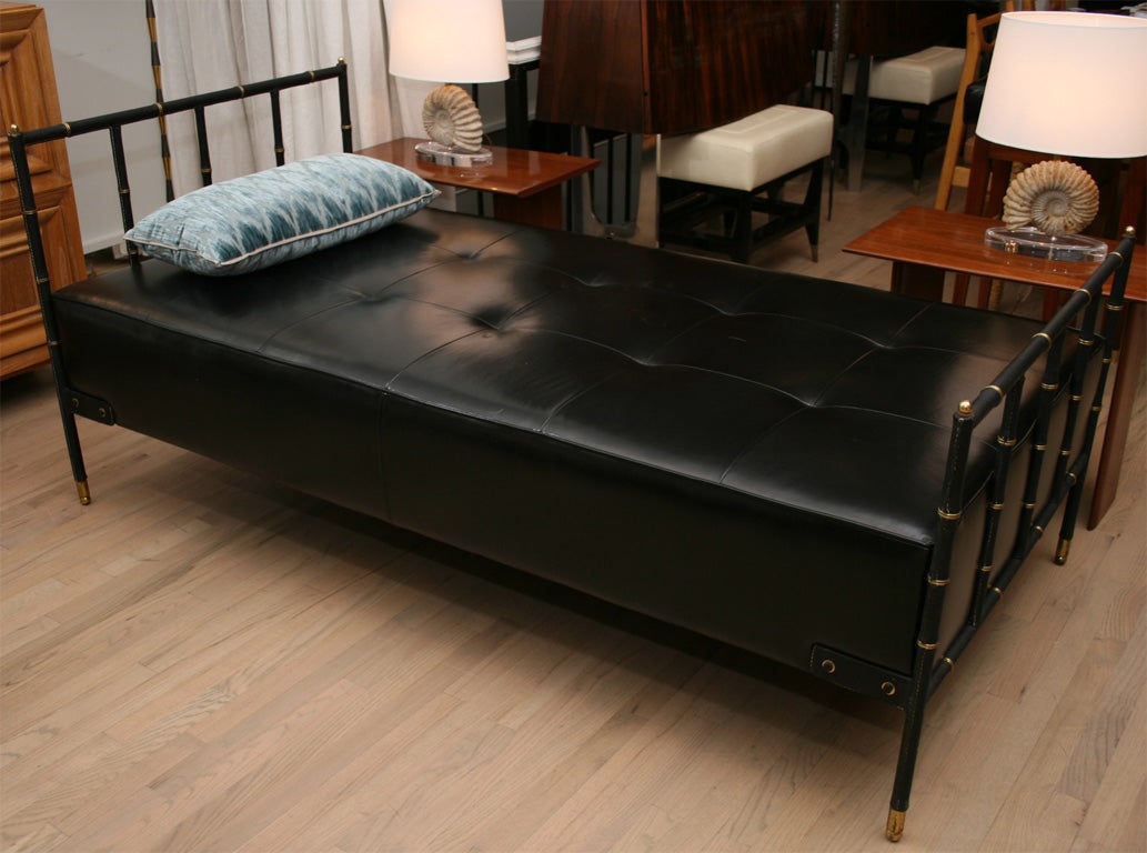 Elegant daybed by Jacques Adnet, the head boards are covered in the classic faux bamboo leather with brass details. The bed itself is newly upholstered in supple black leather.