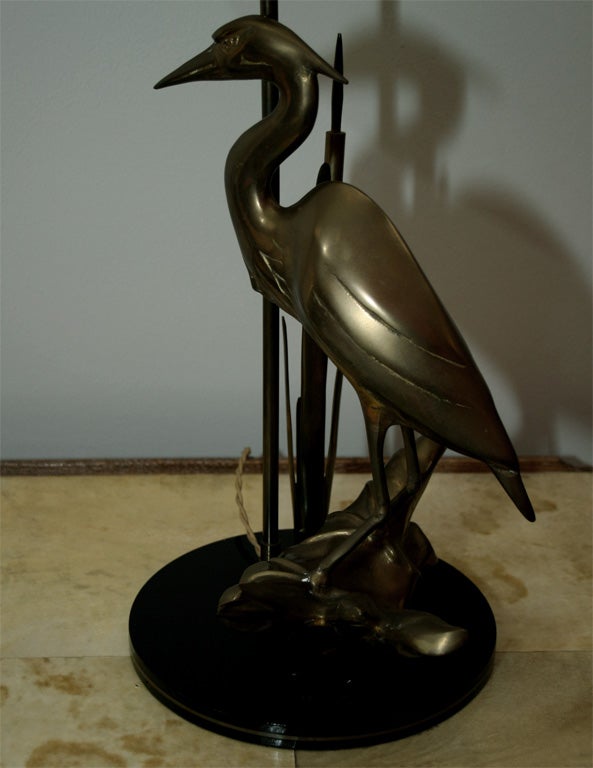 Elegant lamp made of bronze resting on a black lucite base. The bronze part represent a stork amid reeds, very realistic and well executed.