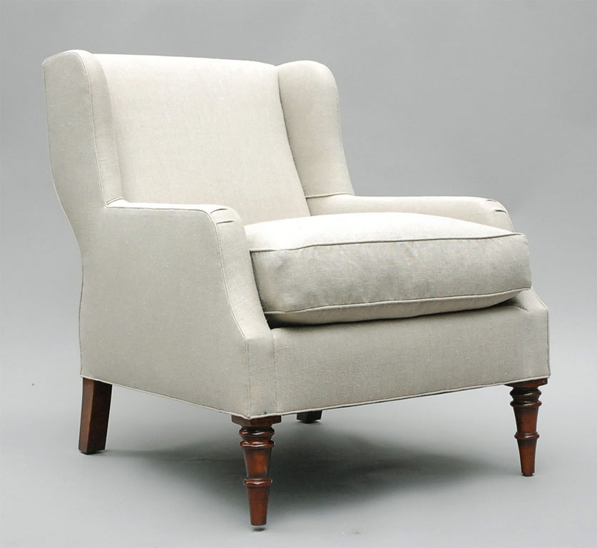 The Selby by Lee Stanton Editions is a short winged armchair with rounded and beveled tapered wood feet, upholstered in a cream-colored Belgian linen or customers own material (COM) and includes a 25/75 down envelope and foam core insert. $150
