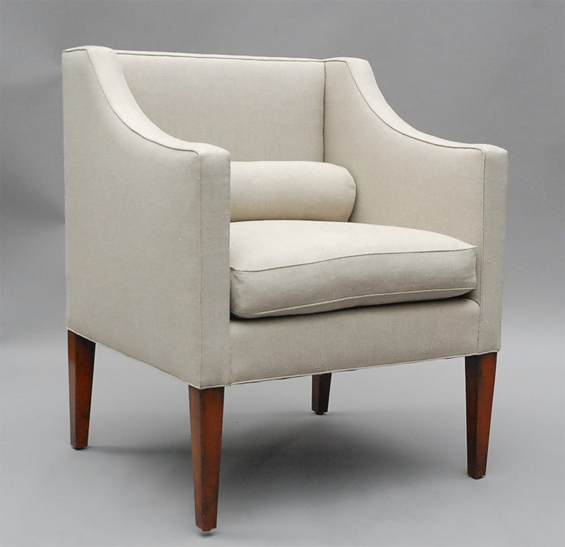 Der Wilton von Lee Stanton Editions ist ein Sessel mit gerader Rückenlehne, elegant geschwungenen Armlehnen und spitz zulaufenden Holzfüßen, gepolstert mit cremefarbenem belgischem Leinen oder einem Material nach Wahl des Kunden (COM) und mit einer
