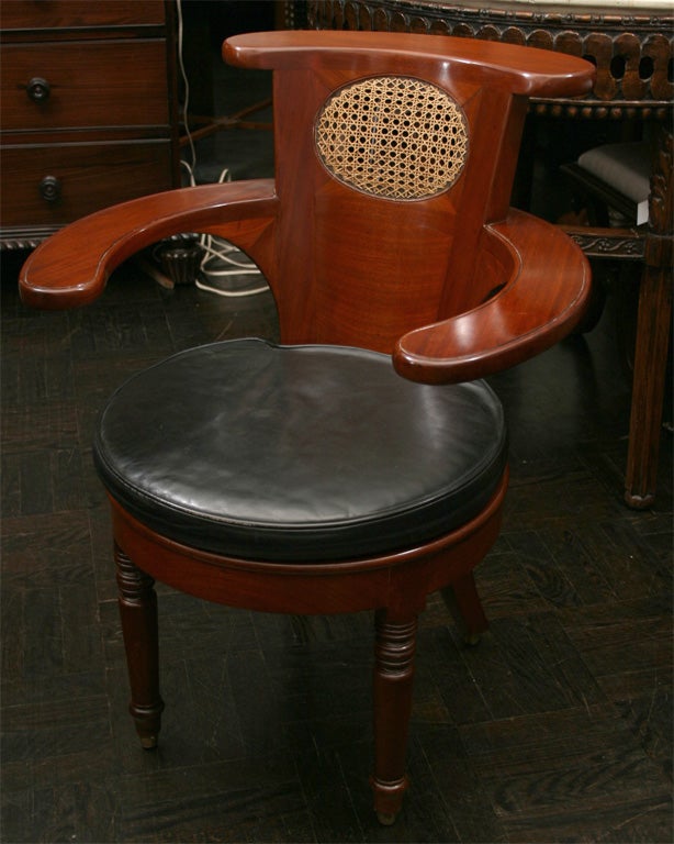Mid-19th century mahogany desk chair with voyese style back and inset caned oval in splat, flat arms rounded seat and apron on turned legs.