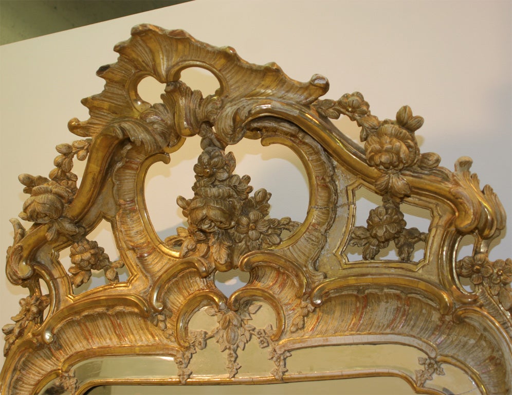 A Swedish Rococo gitwood mirror, Third Quarter 18th Century, the divided mirror plate surrounded by a molded giltwood frame with a beveled glass panel, surmounted with a pierced shell, foliate and scrolled crest, the lower section with similar