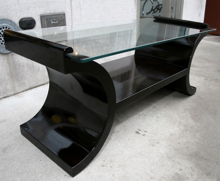 Art Deco cocktail table in ebonized walnut with modernist scroll design.  Features a bottom tier for storage.  This piece has been mint restored.