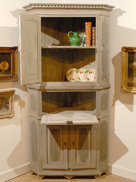 A Swedish Gustavian period painted grey and blue corner cabinet from the late 18th century, with dentil molding, reeded patterns and canted sides. Born in Sweden during the later years of the 18th century, this corner cupboard features a cornice