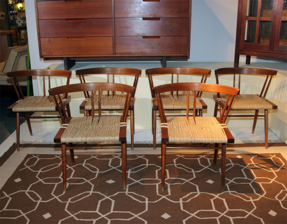 A beautiful example of this popular Dining chair by George Nakashima. Black Walnut seat frame and back rail supported by four tapered Black Walnut legs. Hand shaped Hickory spindles support Walnut top rail.Natural Grass Caning woven over seat frame