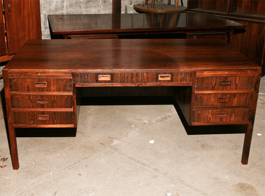 Large rosewood desk, Danish Modern cabinet maker, mid-century modern, having three drawers on either side of knee-hole, pull-out writing slides, and beautifully figured rosewood back