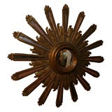 An Elaborately Carved Giltwood Sunburst Form Convex Mirror