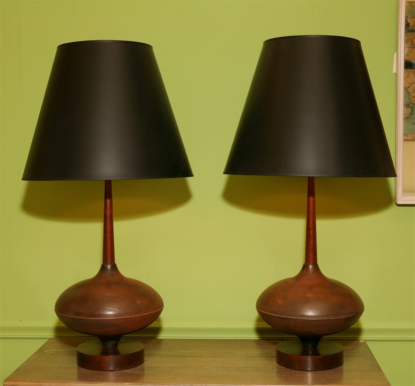 A matched pair of tall table lamps, with elliptical brass centers and thin, tapered, walnut stem. Playful, organic design, with an interesting use of materials.