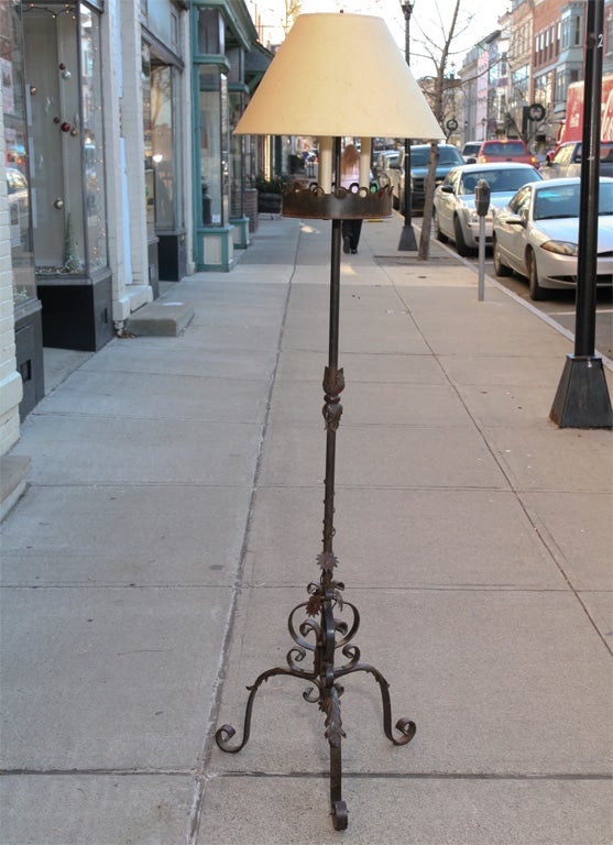 This hand-wrought floor lamp originally would have been intended for use with pillar candles. Currently three sockets and a center shaft for a shade have been added to make it into a floor lamp. The iron work is very nice and includes not only