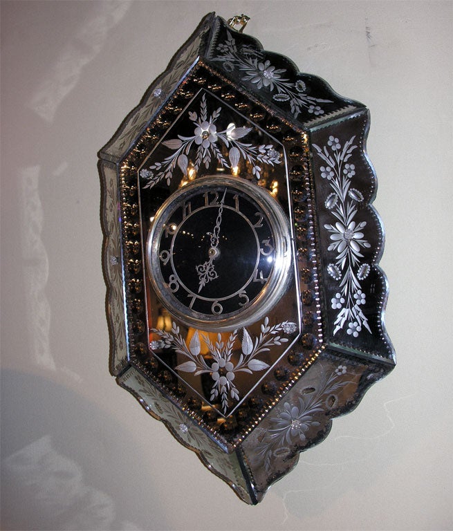 Venetian six-sided scalloped mirrored paneled wall clock with allover etched floral design surrounding a black dial with silver numbers and pierced hands.  Converted to battery operated.