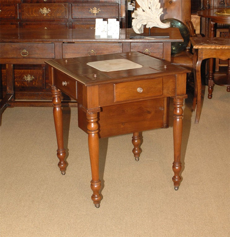 A charming and unusual mid-19th century tea merchants table. The top includes four inset tea boxes along with an inset square piece of marble where a hot water urn stood. There is a large enclosed locking shelf under the table.