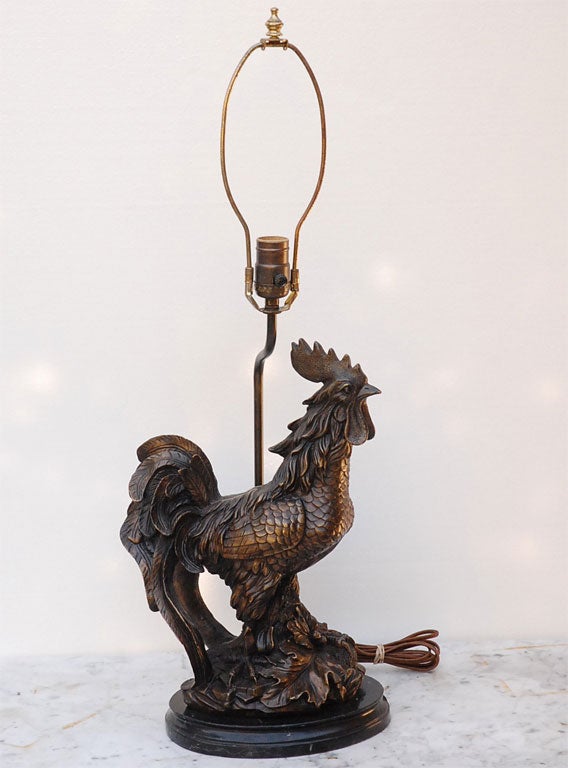 Cast bronze rooster on black marble base lamp. Figurine arm with socket at back of bird. Wonderful casting with acorns, leaves and branches at the birds feet. Beautiful patina to the metal.