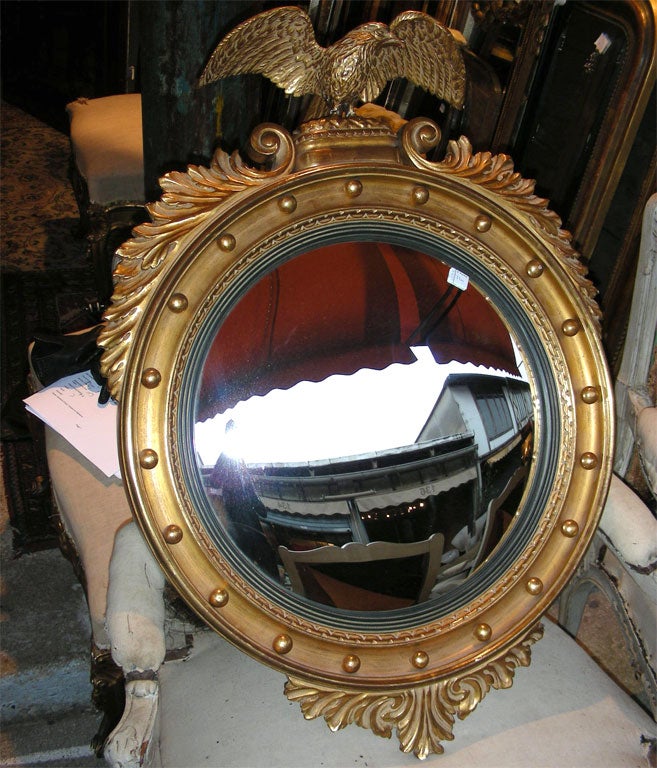 1940s convex mirror framed in gilt wood topped by an eagle with spread wings.