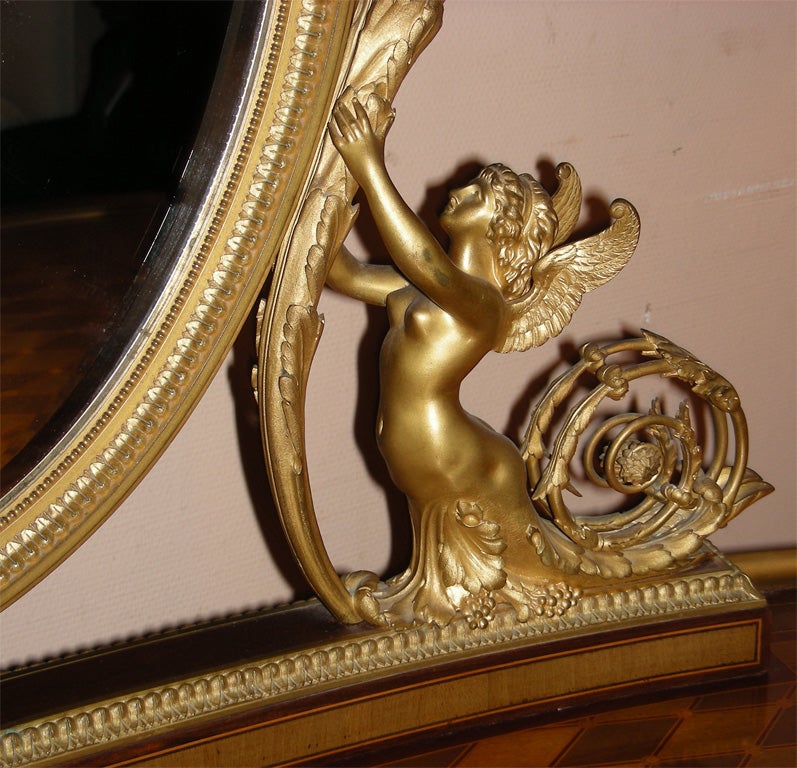 Very beautiful Napoleon III vanity table in mahogany, tulip-wood and amaranth, with gilt bronze fittings. Bevelled mirror supported by handsome statuettes of winged naked females holding up a candlestick, clawed legs. No electric wiring.